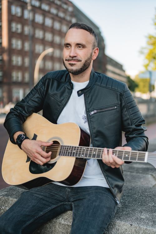 Mann spielt auf seiner Gitarre in der Hamburger Innenstadt